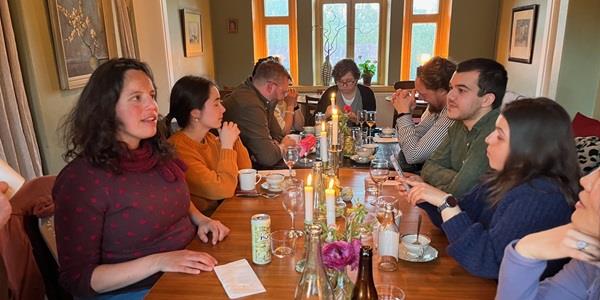 Center member sitting around a wooden dining table eating and chatting