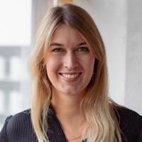 Photo of Anika Schröder. Anika is smiling in the photo. She has long blond hair and is wearing a black shirt.