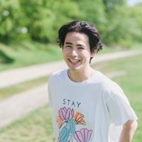 Photo of Kei Kato. He has black hair and is wearing a white T-shirt with flowers and the letters "STAY" printed on the front.
