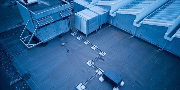 Photo showing the solar server on ITUs roof. Two solar panels are connected with wires to a black box. The photo is tinted with a bluish hue.