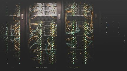 dark picture with servers on server racks with colourful wires